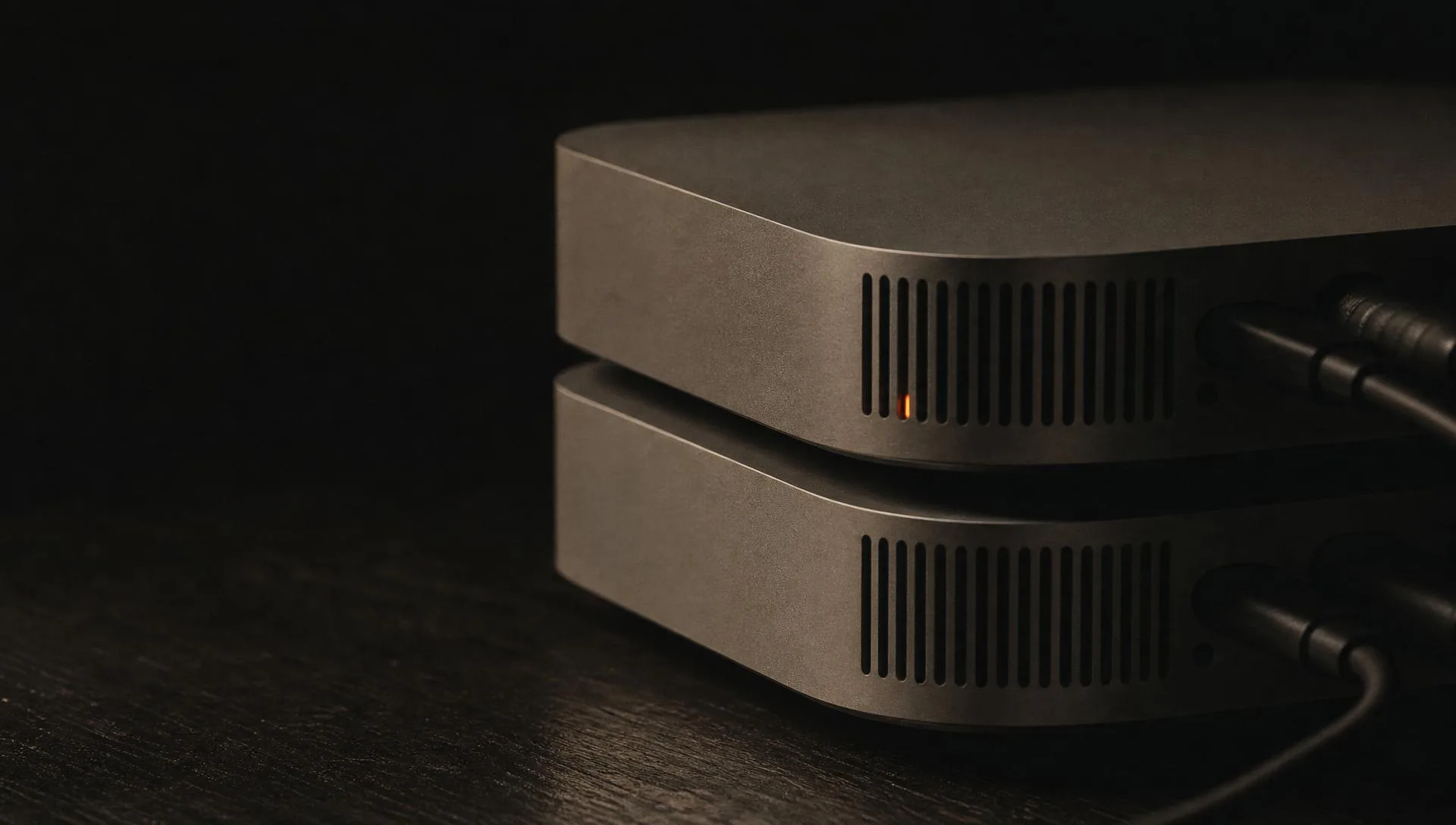 Close-up of stacked mini computers in darkness with a single orange status light.