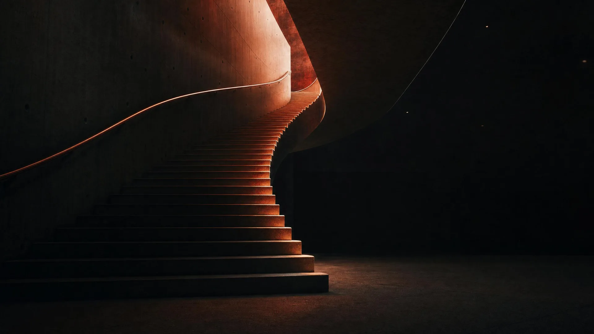 A sculptural staircase ascending into shadow, its leading edges lit warm.